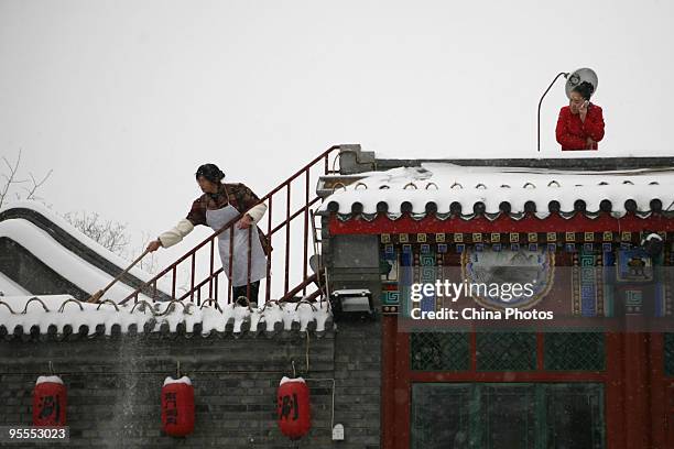 Woman clears snow on the roof at the Shichahai Lake area on January 3, 2010 in Beijing, China. The biggest snowfall in nearly 60 years blanketed...