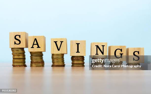 saving text written on wooden block with stacked coins - wooden block stockfoto's en -beelden