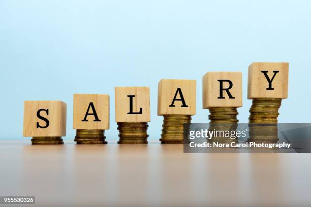 salary text written on wooden block with stacked coins - carol grow stock-fotos und bilder