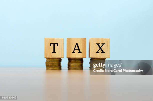 tax text written on wooden block with stacked coins - irc imagens e fotografias de stock