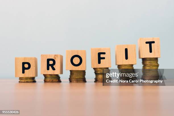 profit text written on wooden block with stacked coins - wooden block stockfoto's en -beelden