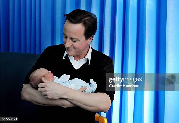 In this handout image supplied by the Conservative Party, Leader of the Conservative Party David Cameron holds John Bowden, who was born at 9.40am on...