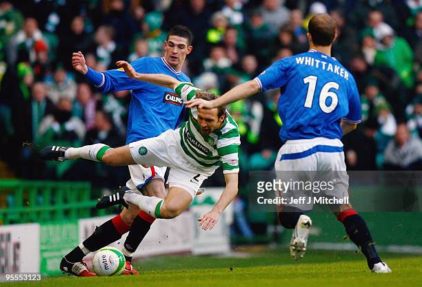 Andreas Hinkel of Celtic is tackled by Kyle Lafferty and Steven Whittaker of Rangers during the Scottish Premier League match between Celtic and...
