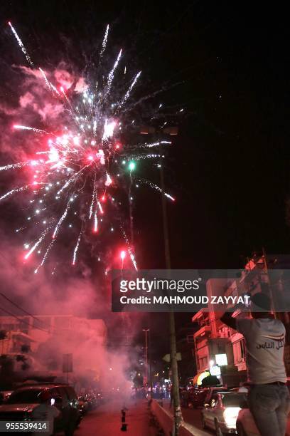 Supporter of Oussama Saad takes a picture of fireworks as he celebrates the candidate's victory in the general elections, in Sidon, on May 6, 2018. -...