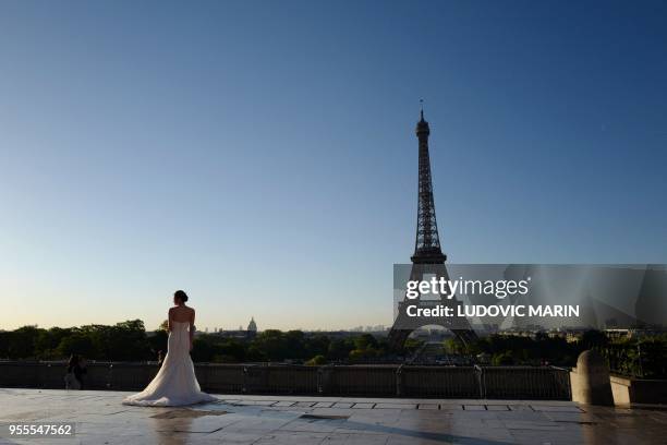 Bride poses in front of the Eiffel tower at sunrise on Trocadero square on May 7 in Paris