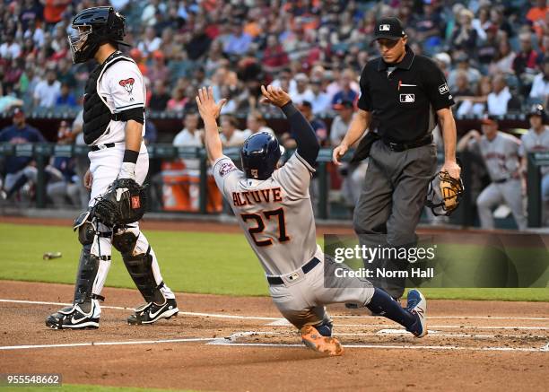 Jose Altuve of the Houston Astros slides into home plate against the Arizona Diamondbacks as home plate umpire Dan Iassogna looks on at Chase Field...