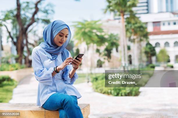 portrait de femme malaisienne avec hijab en utilisant le téléphone et envoyer des sms - sms'en photos et images de collection