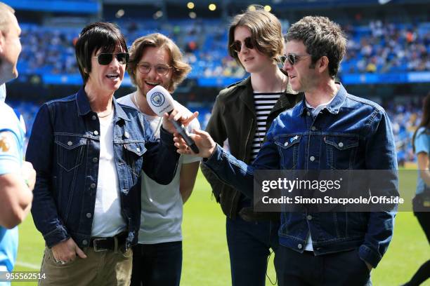 Musician Noel Gallagher hands the microphone to fellow rock star Johnny Marr ahead of the Premier League match between Manchester City and...