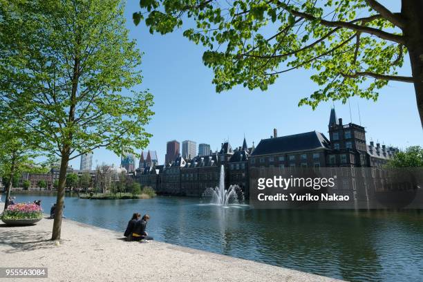 People sit in front of the Hofvijver, or 'Court Pond' of Binnenhof on May 3 in The Hague, Netherlands.