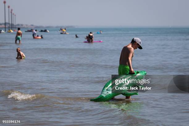 Boy takes an inflatable crocodile into the water from the beach during the warm weather on Bank Holiday Monday on May 7, 2018 in Bognor Regis, United...