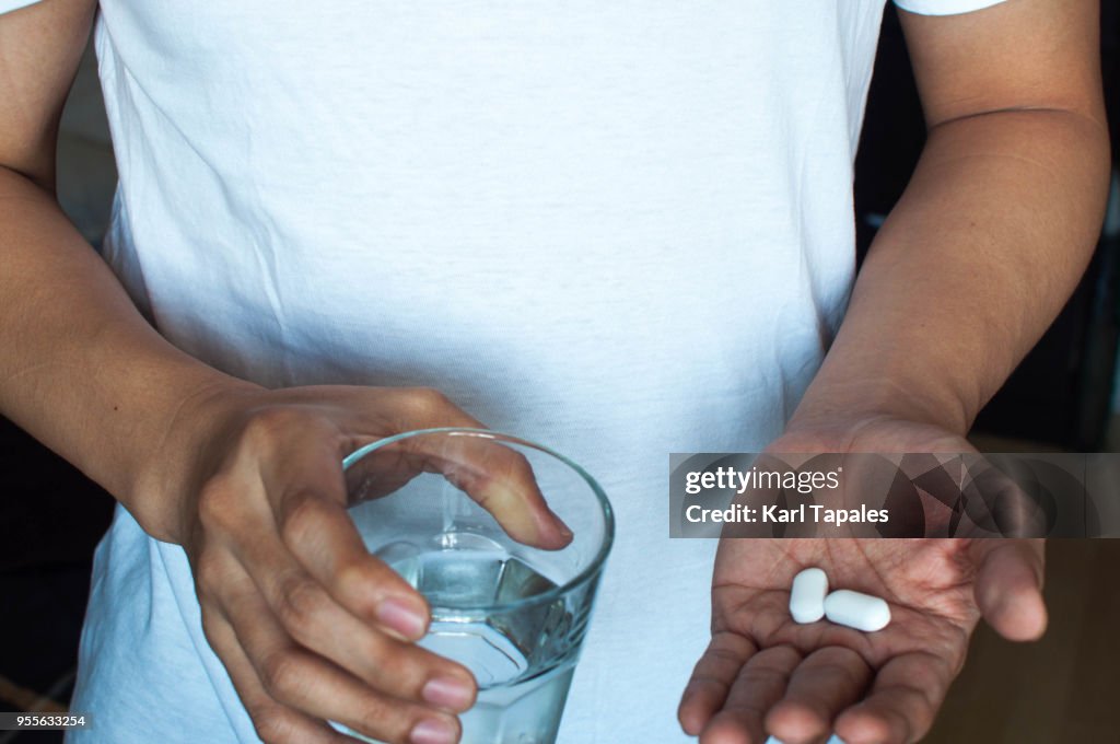 A man is drinking a medicine pill