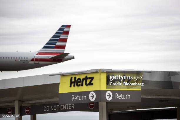 An American Airlines Group Inc. Plane flies above the Hertz Global Holdings Inc. Rental location at LaGuardia Airport in the Queens borough of New...