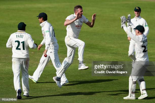 Jake Ball of Nottinghamshire celebrates with team mate Tom Moores after taking the match winning wicket of Hashim Amla during day four of the...