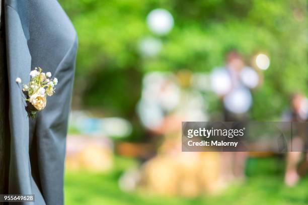 part of a suit jacket with corsage hanging on a tree trunk. - wedding guest gifts stock pictures, royalty-free photos & images