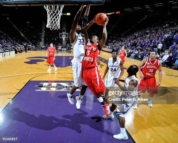 Guard Kendall Cutler of the South Dakota Coyotes drives to the basket against pressure from forward Jamar Samuels of the Kansas State Wildcats in the...