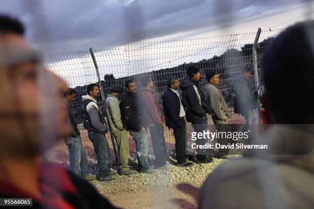 Palestinian labourers line up to cross an Israeli checkpoint as they return to their homes after a day's work in the Jewish state on January 3, 2010...