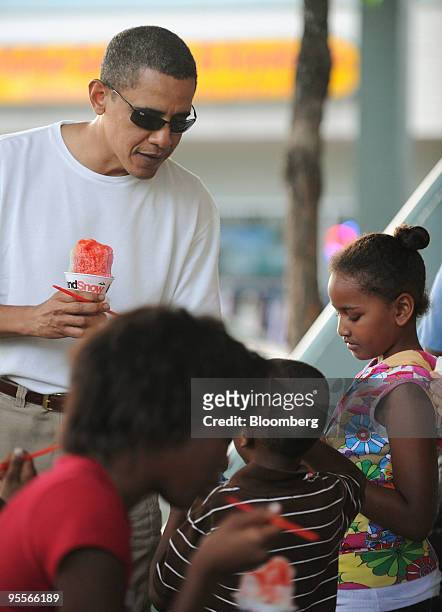 President Barack Obama eats shave ice with his daughter, Sasha, outside the Island Snow shop in Kailua, Hawaii, U.S., on Friday, Jan. 1, 2010. Obama...