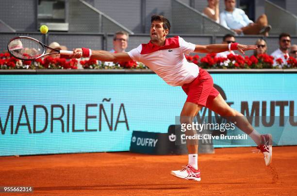 Novak Djokovic of Serbia stretches to play a forehand against Kei Nishikori of Japan in their first round match during day three of the Mutua Madrid...