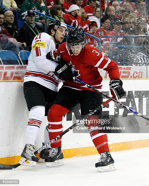 Travis Hamonic of Team Canada body checks Mauro Jorg of Team Switzerland during the 2010 IIHF World Junior Championship Tournament Semifinal game on...