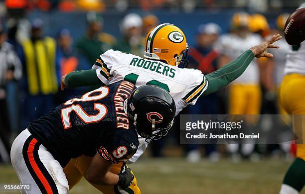 Aaron Rodgers of the Green Bay Packers tosses the ball as he is brought down by Hunter Hillenmeyer of the Chicago Bears at Soldier Field on December...