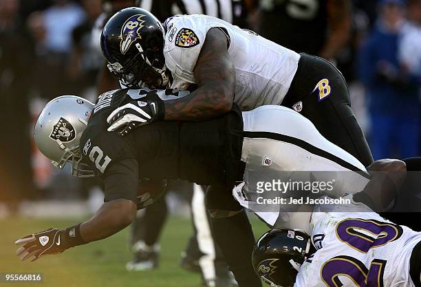 Terrell Suggs of the Baltimore Ravens tackles JaMarcus Russell of the Oakland Raiders during an NFL game at Oakland-Alameda County Coliseum on...
