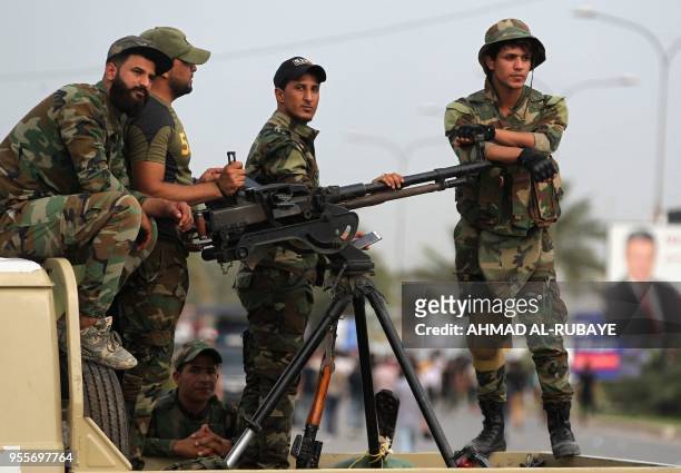Iraqi fighters of the Hashed al-Shaabi units stand guard during a campaign gathering for the Fateh Alliance, a coalition of Iranian-supported militia...
