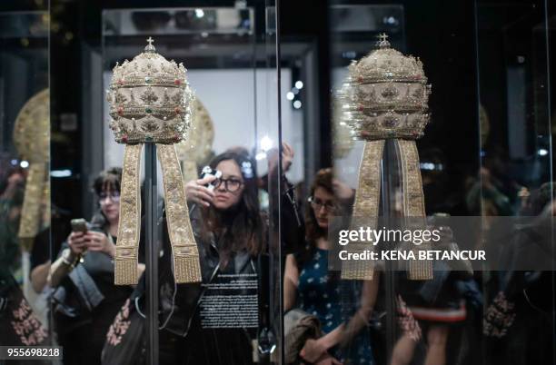 Members of the media look at Papal Tiaras from the Sistine Chapel during the press preview for the annual fashion exhibit "Heavenly Bodies: Fashion...