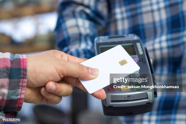 close up of hand using credit card swiping machine to pay. hand with creditcard swipe through terminal for payment - checkout register stock pictures, royalty-free photos & images