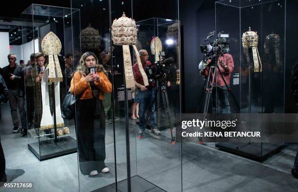 Members of the media look at Papal Tiaras from the Sistine Chapel during the press preview for the annual fashion exhibit "Heavenly Bodies: Fashion...