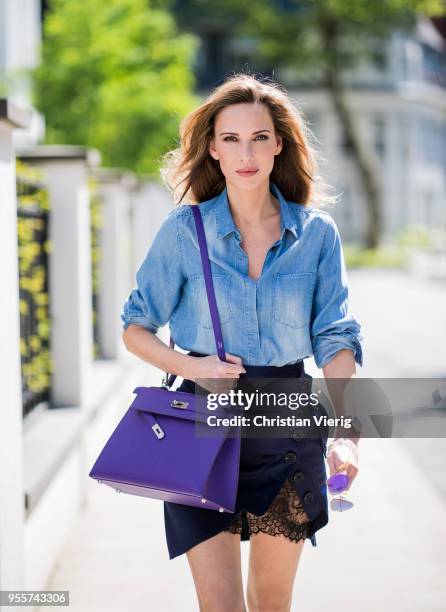 Alexandra Lapp wearing a blue satin skirt with lace by Self-Portrait, a light blue denim shirt by H&M, a purple Kelly bag by Hermes, Denim Jazz Calf...