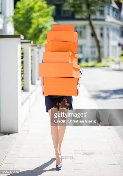 Alexandra Lapp carrying several Hermes cartons wearing a blue satin skirt with lace by Self-Portrait, a light blue denim shirt by H&M, Denim Jazz...