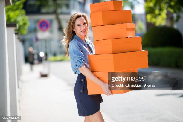 Alexandra Lapp carrying several Hermes cartons wearing a blue satin skirt with lace by Self-Portrait and a light blue denim shirt by H&M on May 5,...