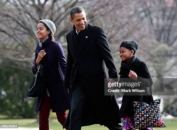 President Barack Obama walks with his daughters Malia and Sasha after they arrive on the South Lawn of the White House on January 4, 2010 in...