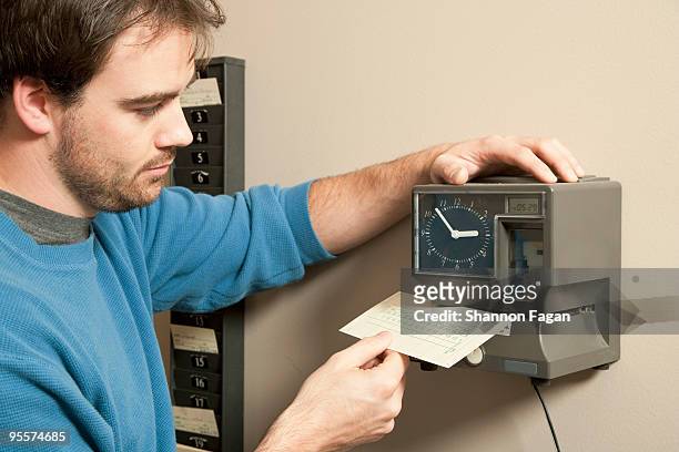 a man marking payroll record with time clock - primo turno foto e immagini stock