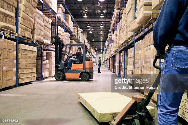 staffs working different tasks in a warehouse - gabelstapler stock-fotos und bilder
