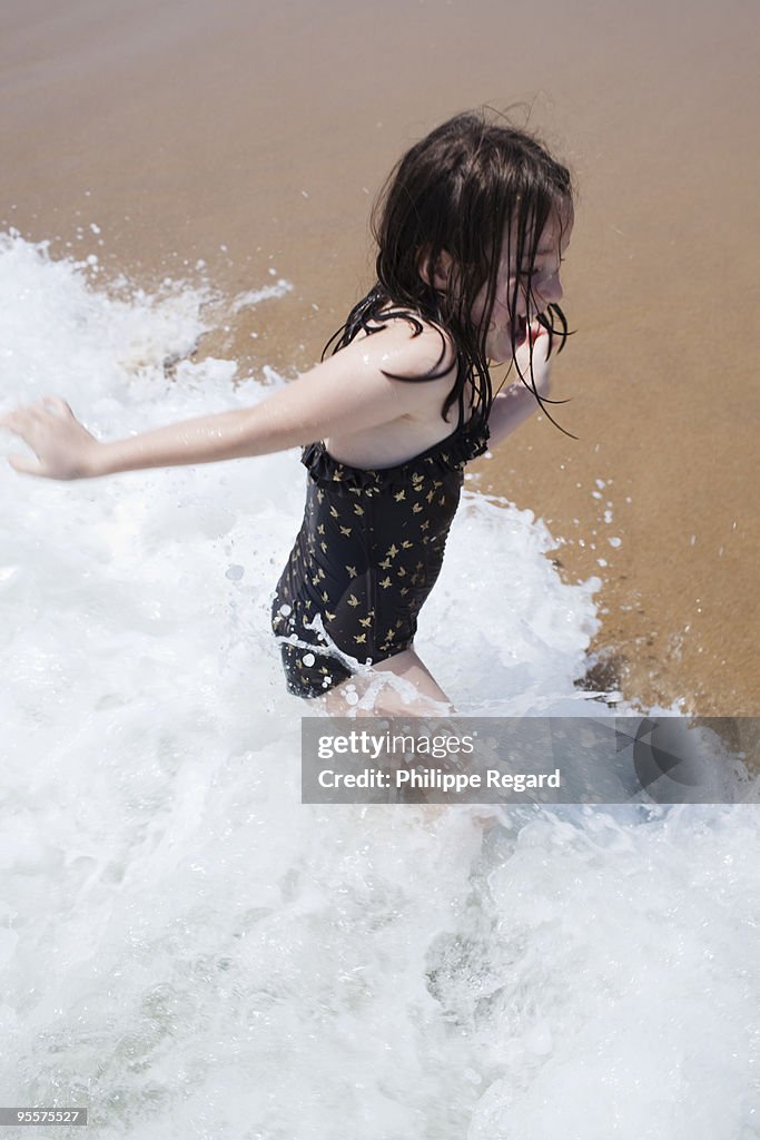 6 years old girl playing in a white foam wave