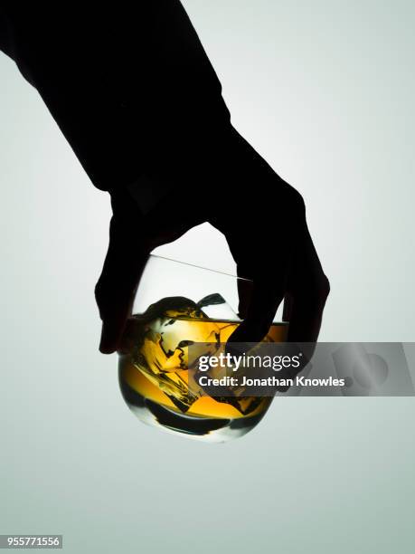 silhouetted male hand holding a glass of whiskey - alkoholism bildbanksfoton och bilder