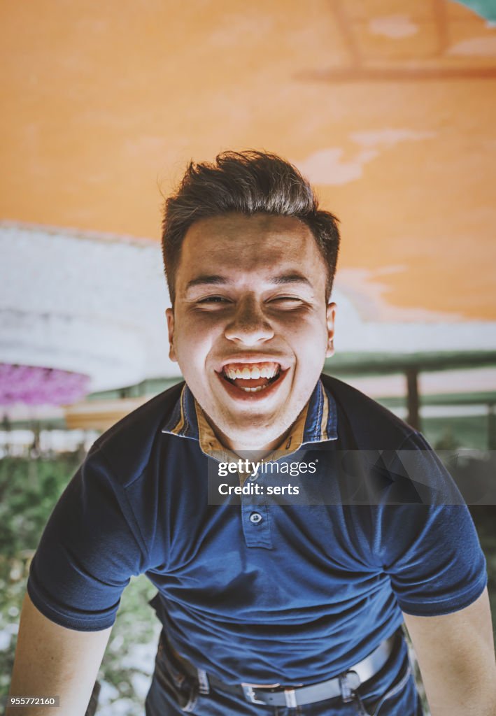 Portrait of happy young man hanging upside down in playground