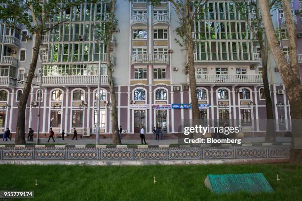 Pedestrians walk past a building on Rudaki Avenue in Dushanbe, Tajikistan, on Saturday, April 21, 2018. Flung into independence after the Soviet...