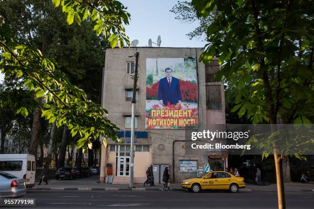 Taxi sits parked below a banner featuring an image of Tajikistan President Emomali Rahmon displayed on a building in Dushanbe, Tajikistan, on...