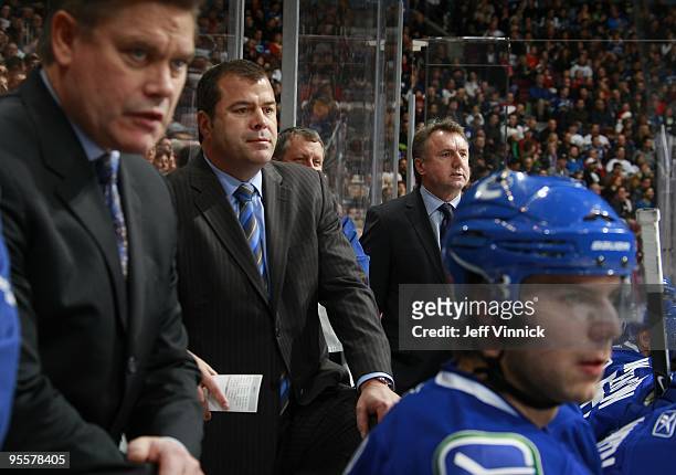 Assistant coach Ryan Walter, head coach Alain Vigneault and associate coach Rick Bowness of the Vancouver Canucks look on from the bench during their...