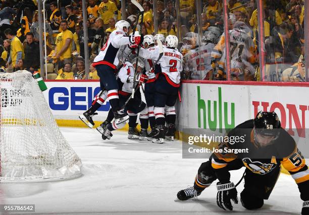 Evgeny Kuznetsov of the Washington Capitals celebrates his overtime goal with teammates in front of Kris Letang of the Pittsburgh Penguins in Game...
