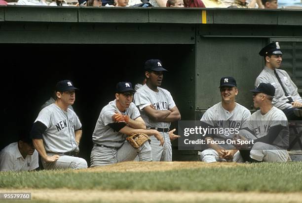 Outfielder Mickey Mantle far of the New York Yankees and Roger Maris second from the right watches the action from the dougout with other teammates...