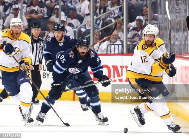 Mattias Ekholm and Mike Fisher of the Nashville Predators race after the loose puck against Mathieu Perreault of the Winnipeg Jets during first...