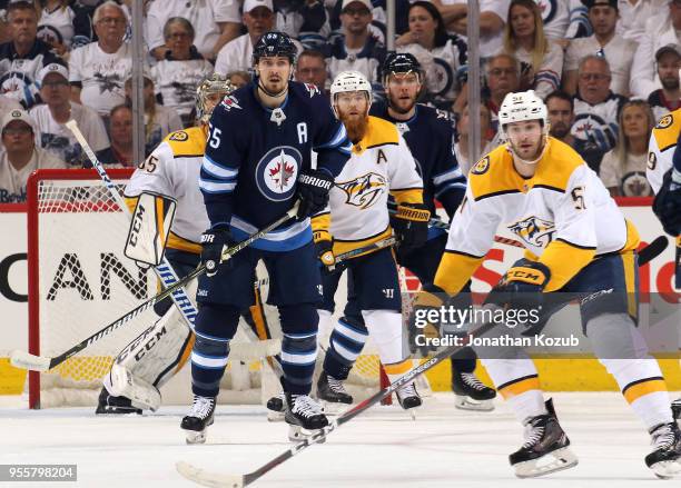 Ryan Ellis of the Nashville Predators stands between Mark Scheifele and Paul Stastny of the Winnipeg Jets as they keep an eye on the play at the...