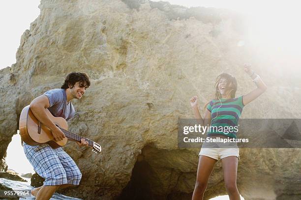 man playing guitar for girlfriend on beach - lens flare young people dancing on beach stock pictures, royalty-free photos & images