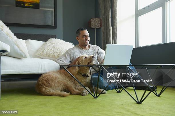 african man using laptop as dog sits nearby - man laptop dog stock pictures, royalty-free photos & images