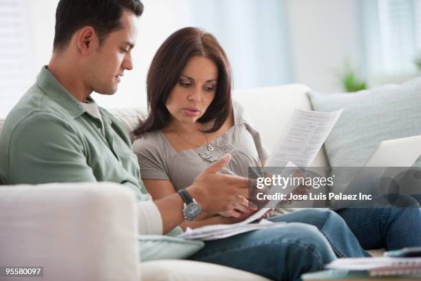 hispanic couple reviewing monthly bills - examining paperwork stock pictures, royalty-free photos & images