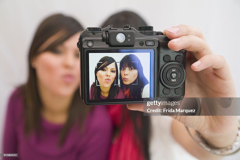 Hispanic friends taking self-portrait with digital camera