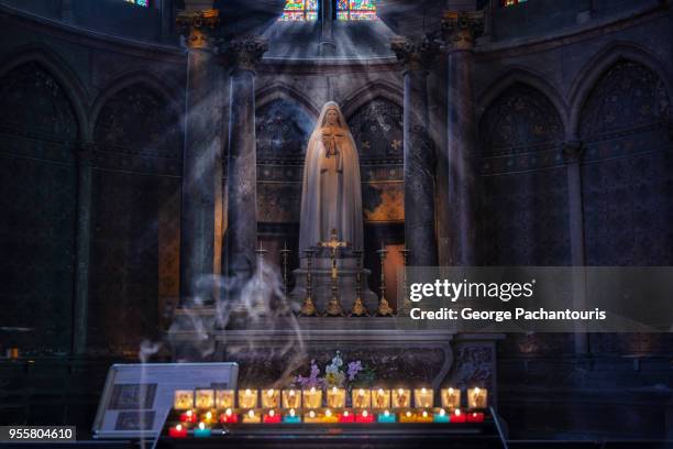 virgin mary statue and candles burning - church burning stock pictures, royalty-free photos & images